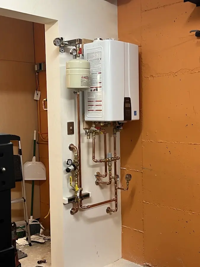 Plumbing technician inspecting water heater connections in Blaine